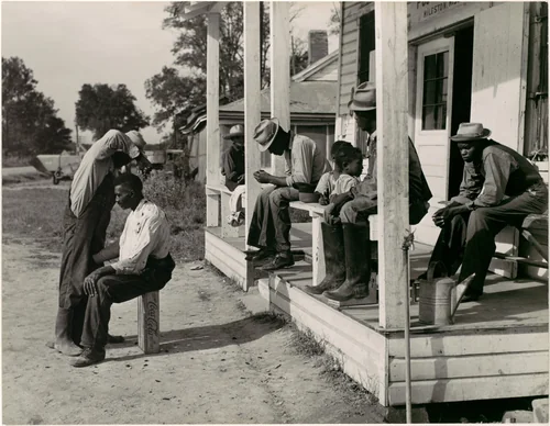 [Haircutting in Front of General Store and Post Office on Marcella Plantation, Mileston, Mississippi] by Marion Post Wolcott, photograph, 1939