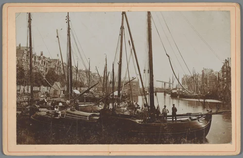 Gezicht op beurtschepen aan het Damrak in Amsterdam by anonymous, photograph, 1880-1900
