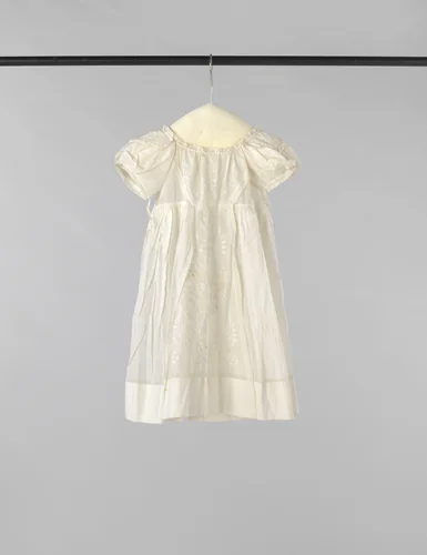 Kinderjurk met hoge taille en achtersluiting met striklinten van witte batist, voor versierd met een breed tussenzetsel plumetis en op de korte pofmouw ook met plumetis. by anonymous, other, 1850-1900