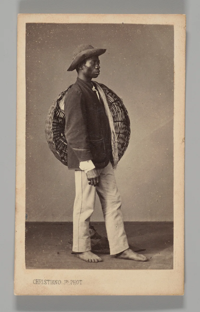 [Studio Portrait: Male Street Vendor Standing in Profile Holding Basket, Brazil] by Christiano Junior, photograph, 1864-1866