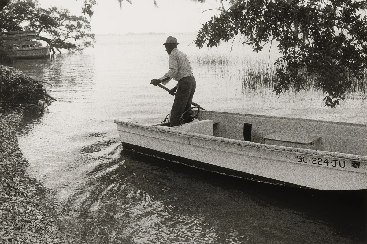 Jake with His Boat Arriving on Daufuskie’s Shore, Daufuskie Island, South Carolina by Jeanne Moutoussamy-Ashe, photograph, 1978