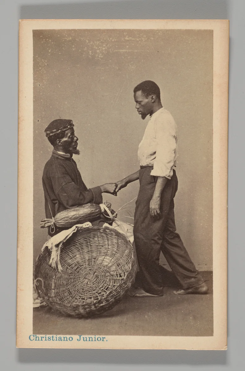 [Studio Portrait: Two Male Street Vendors in Profile, one Seated one Standing, Shaking Hands, Brazil] by Christiano Junior, photograph, 1864-1866