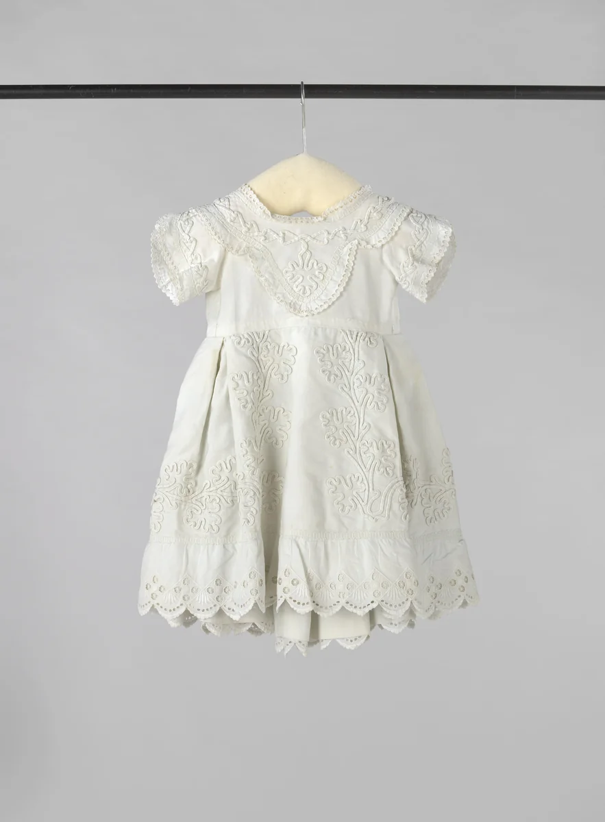 Kinderjurk van witte katoen met een ingeweven ribbel, versierd met soutache, Engels borduurwerk en passement. by anonymous, other, 1870-1880