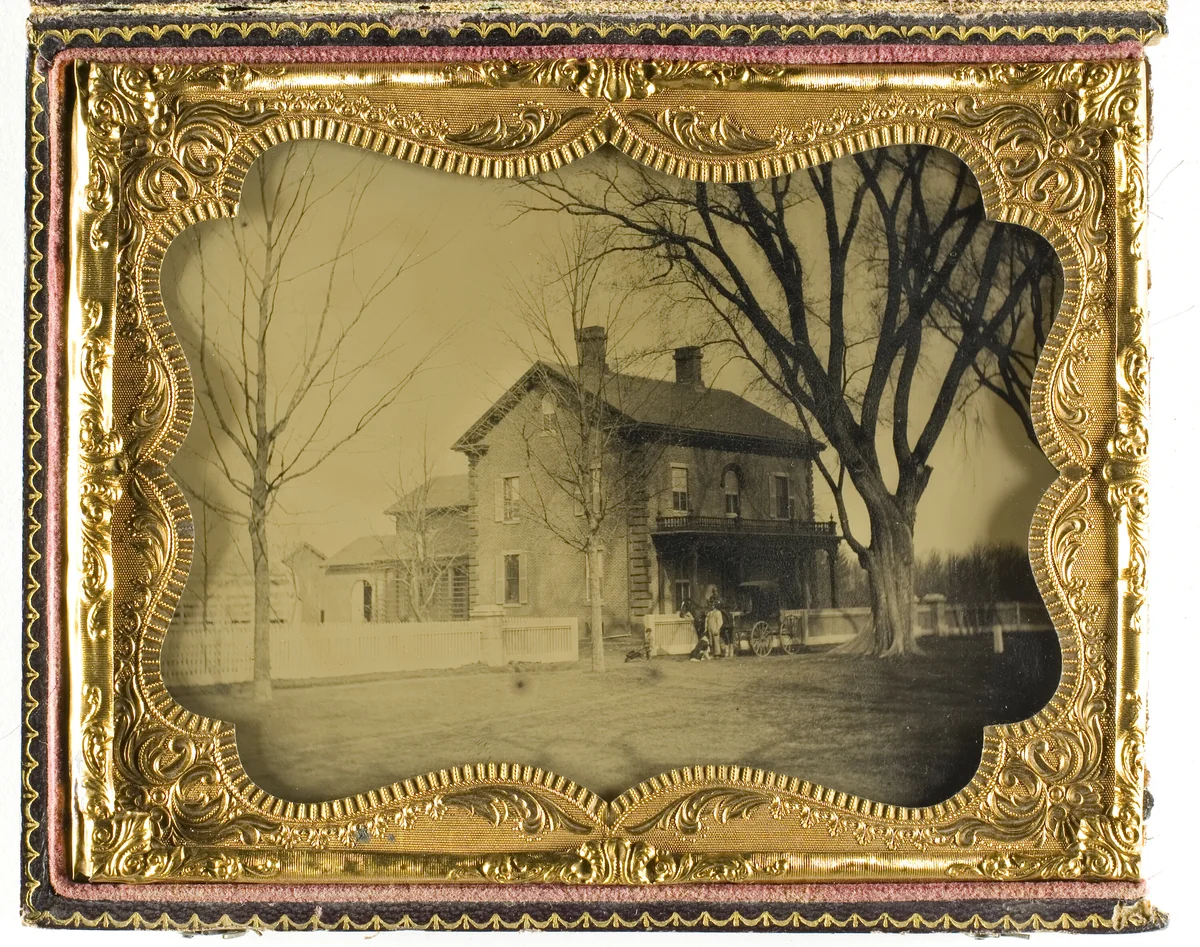 Two and a Half Story Brick Country House with Outbuildings with Ornate Porch and Picket Fence by Artist Unknown, photograph, 1854-1900