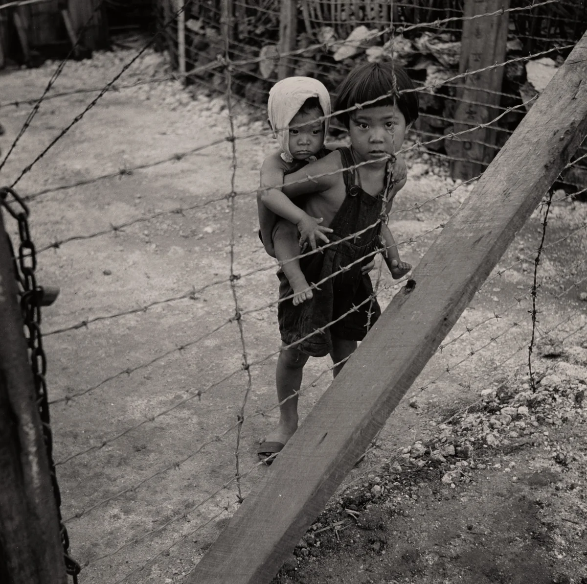 Child with Infant on His Back behind Barbed Wire. Prison for Suspected Collaborators, Guam by Wayne Miller, photograph, 1944