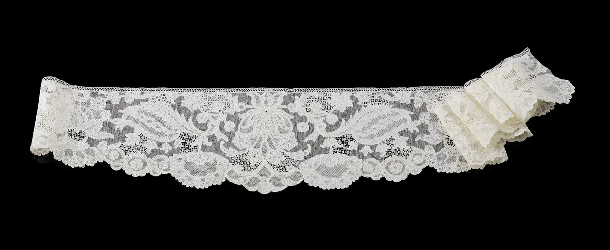 Engageante van naaldkant met symmetrisch patroon met in het midden een vlammende bloem geflankeerd door langgerekte gevederd bladeren waaronder grote hangende waaiervormige bloemen by anonymous, other, 1725-1735