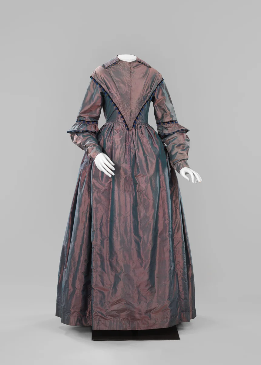 Japon met platliggende kraag, lange mouwen en een puntvormig voorlijf van paarsgroene changeantzijde, gevoerd met geglansd paars katoen; passementen in blauw, zwart en beige by anonymous, other, 1840-1850