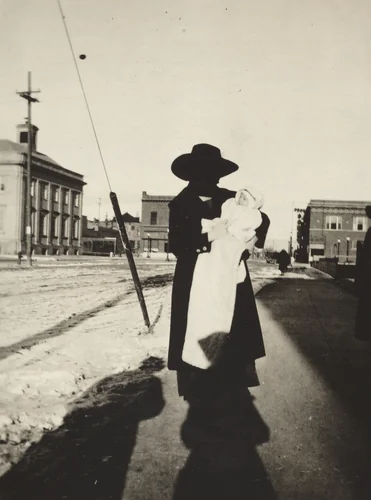 Untitled (Woman holding baby on street) by American 20th Century, photograph, 1890-1919