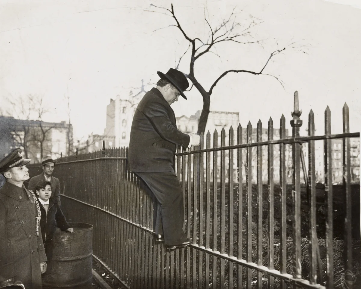 "Mayor La Guardia Climbs a Fence" by Times Wide World Photos, photograph, 1935