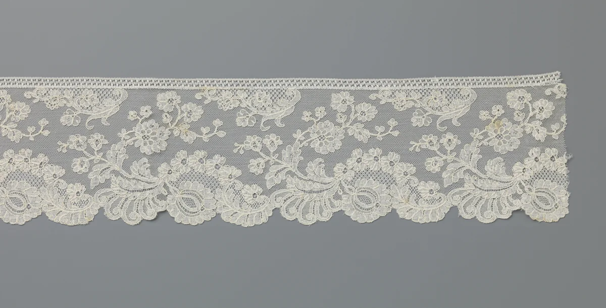 Strook machinale kant met een grote bloem onder een bloemenboogje met daaroverheen een terugbuigende bloementak by anonymous, other, 1885