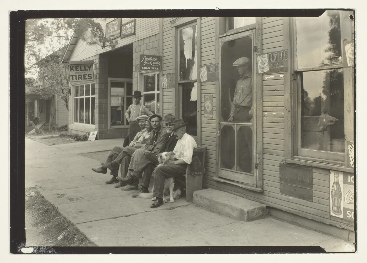 Men With Dog Sitting On Bench In Front Of General Store by Lewis Wickes Hine, photograph, 1905-1915