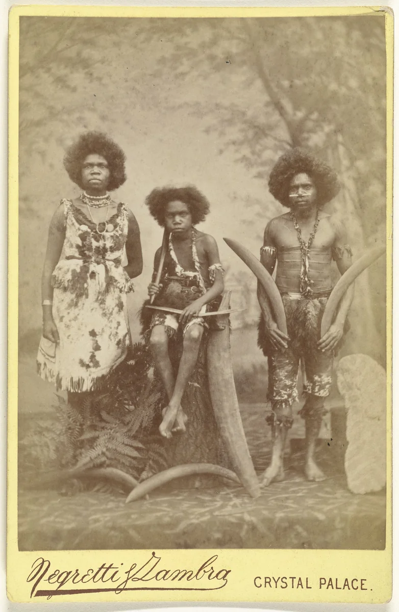 Groepsportret van drie oorspronkelijke bewoners van Australië; Jenny, haar zoon Toby en Billy in het Crystal Palace te Londen tijdens hun Europese tournee onder leiding van Richard A. Cunningham by anonymous, photograph, 1884
